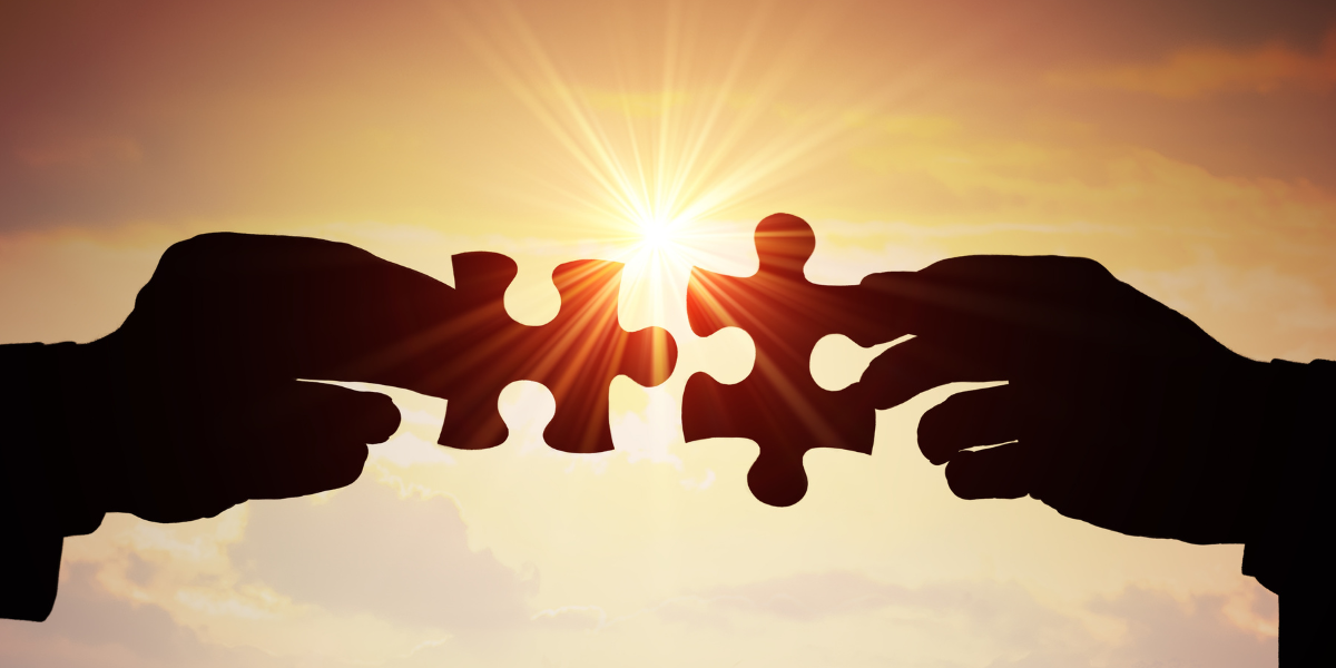 Two puzzle pieces held against a setting sun, symbolic of the partnership displayed in this case study of Saginaw Bay Underwriters.